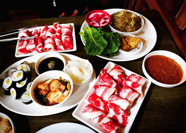 raw samgyupsal, kimbap, kimchi, japchae, and samjang