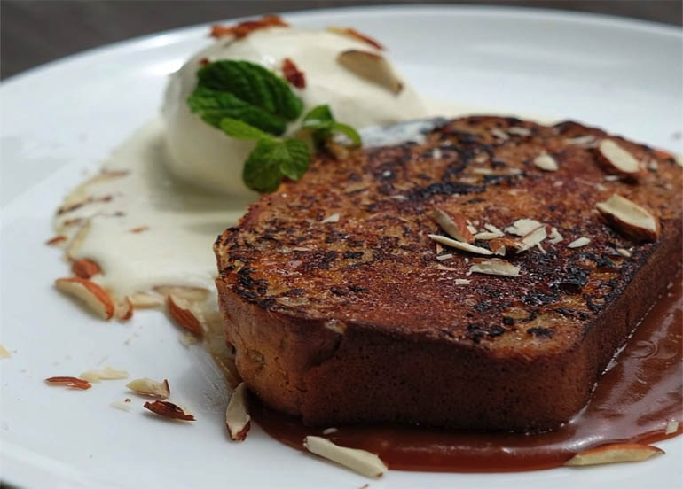 Bread Pudding from Refinery topped with almonds, garnish, and a side of vanilla ice cream