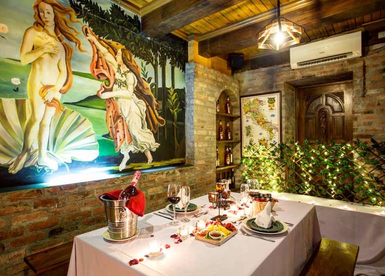 Galileo Enoteca interior featuring a romantic dining set-up and a mural